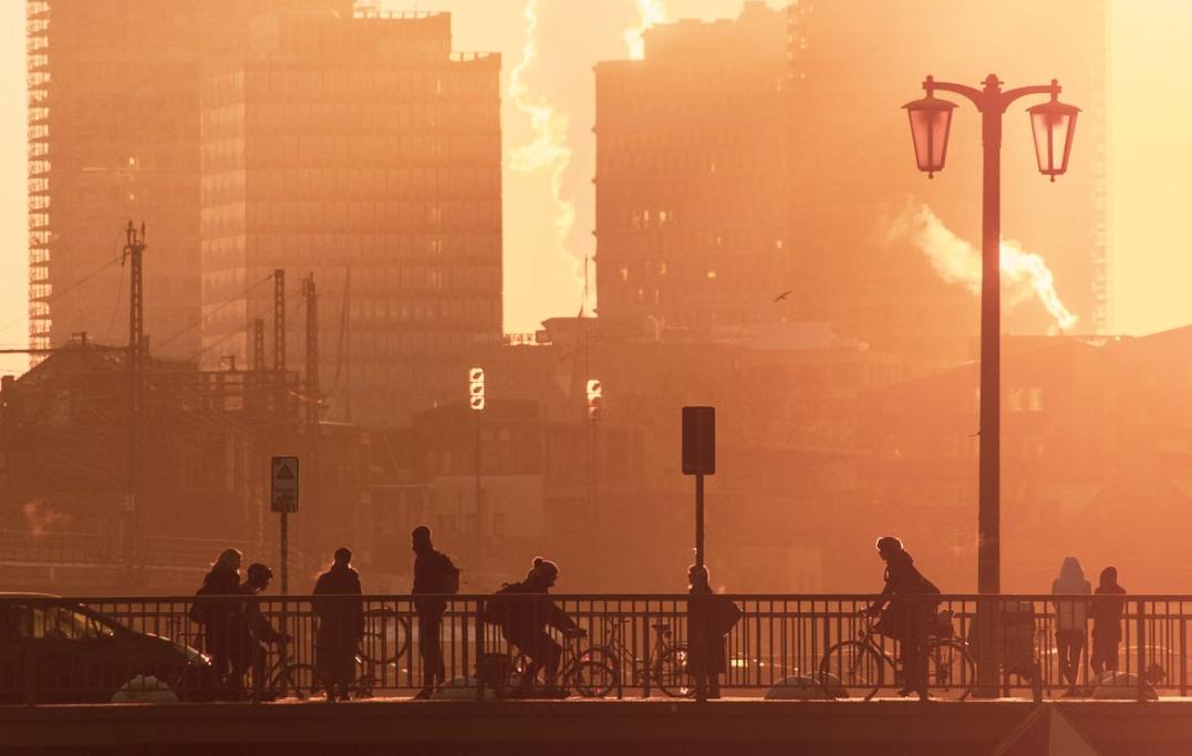 Una calle europea casi vac&iacute;a al mediod&iacute;a durante una ola de calor, con luz solar intensa y sombras n&iacute;tidas